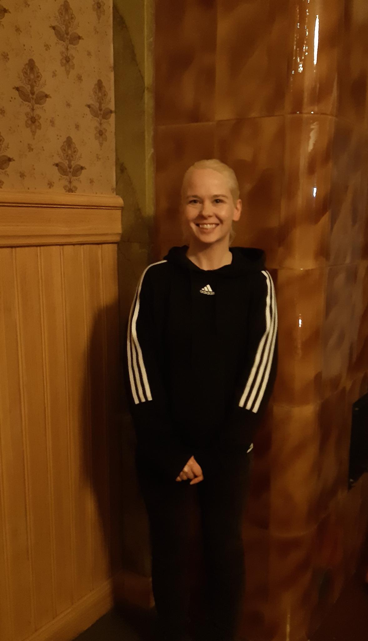 Sonja Savonlinnan vapaaehtoinen seisoo ruskeaa seinää vasten