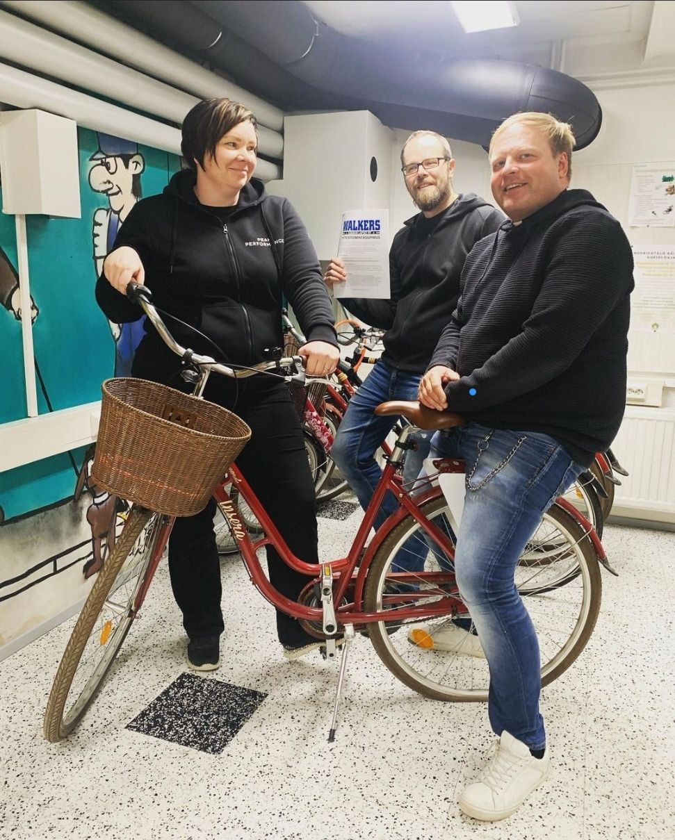 Kolme aikuista sisällä polkupyörän ympärillä