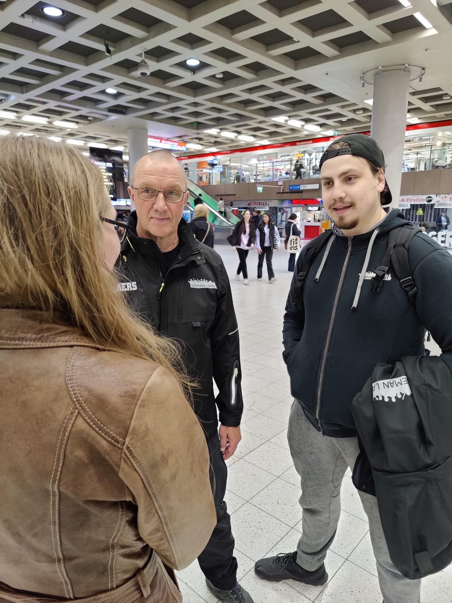 Kaksi nuorisotyöntekijää juttelemassa kuvassa selin olevalle pitkähiuksiselle nuorelle
