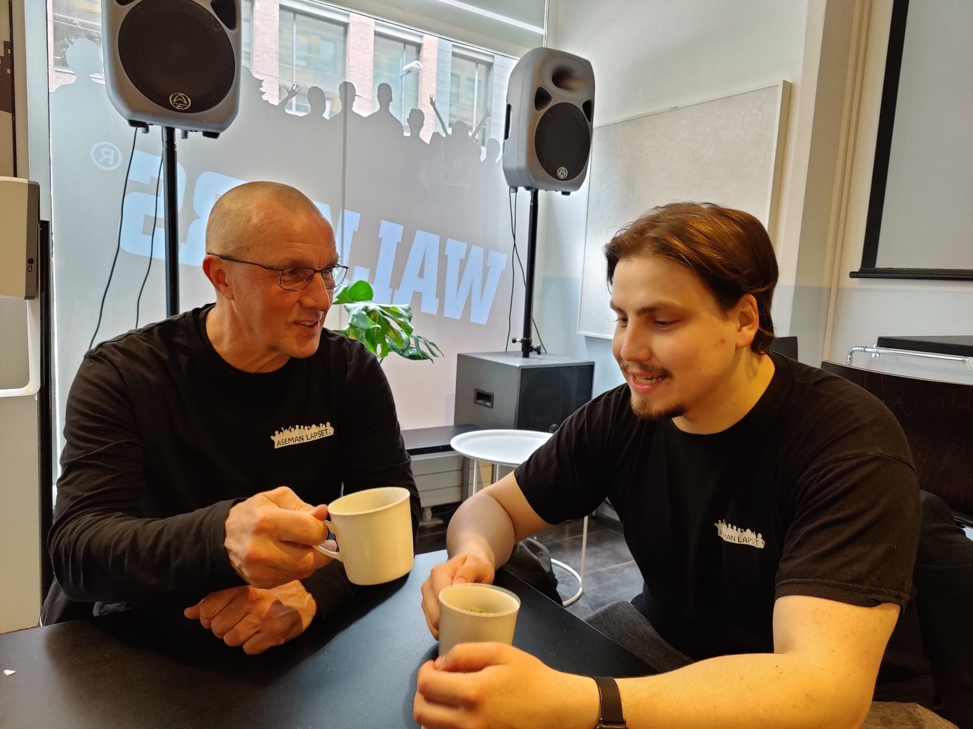 Kaksi ihmistä istuu pöydän ääressä kahvilla