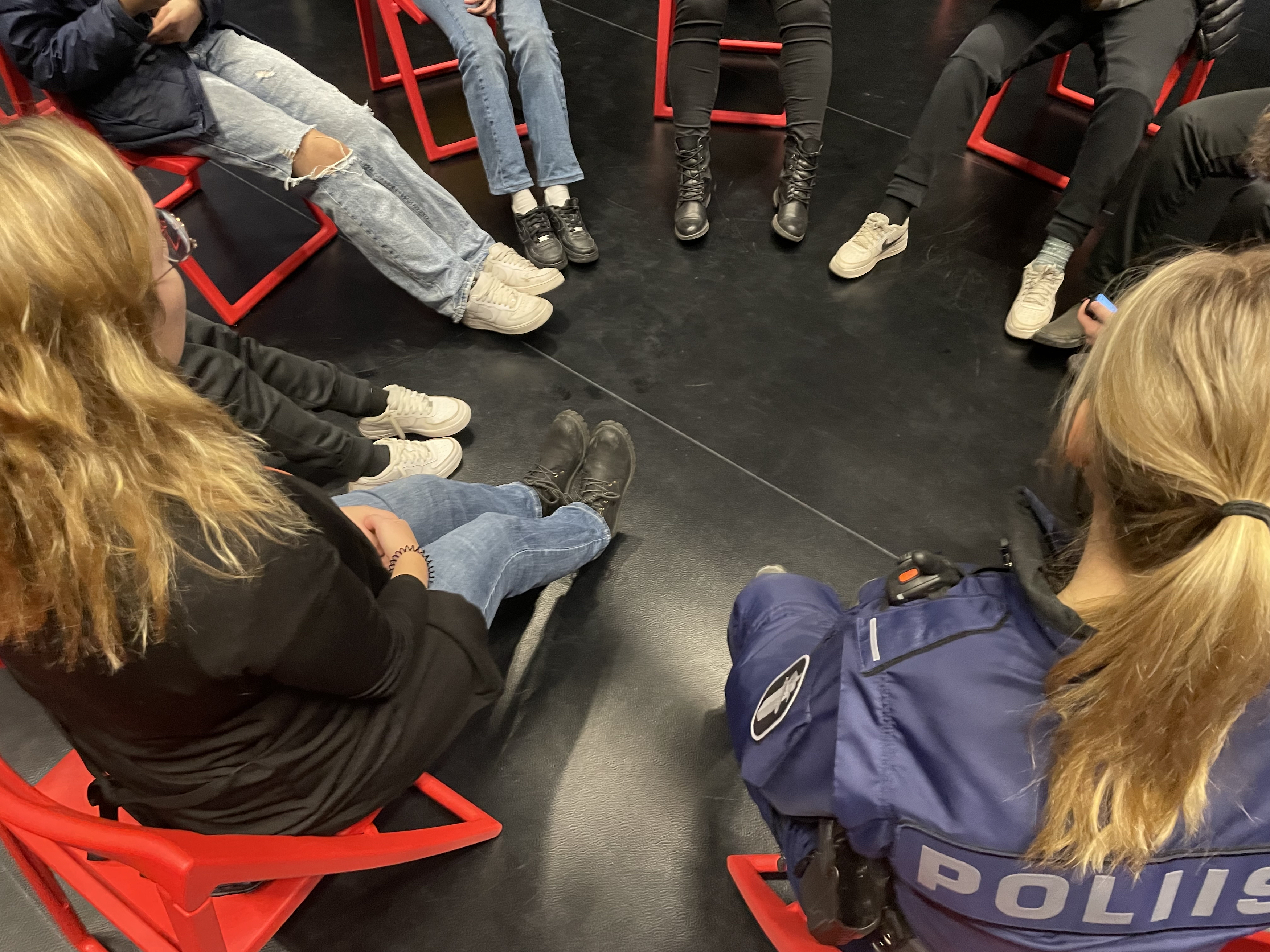 Nuoret istuvat conferencing-sovittelussa ringissä sovittelijan ja poliisin kanssa. Kasvoja ei näy.